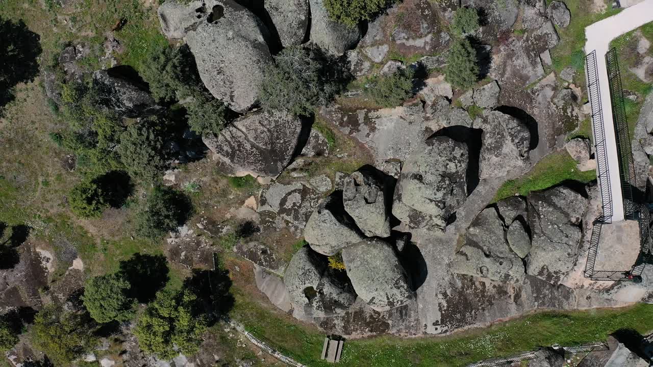 vuelo en ascenso y con una vista de arriba hacia abajo con un dron de un punto de vista en una zona de rocas de granito y a una cierta altura la filmación comienza a girar, una carretera aparece con un coche toledo españa