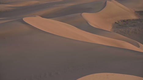 Panning-up-across-beautiful-sand-dune-field-with-mountains-in-background