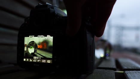 man hand setting up camera for recoding video with crystal ball reflects a passing train at station