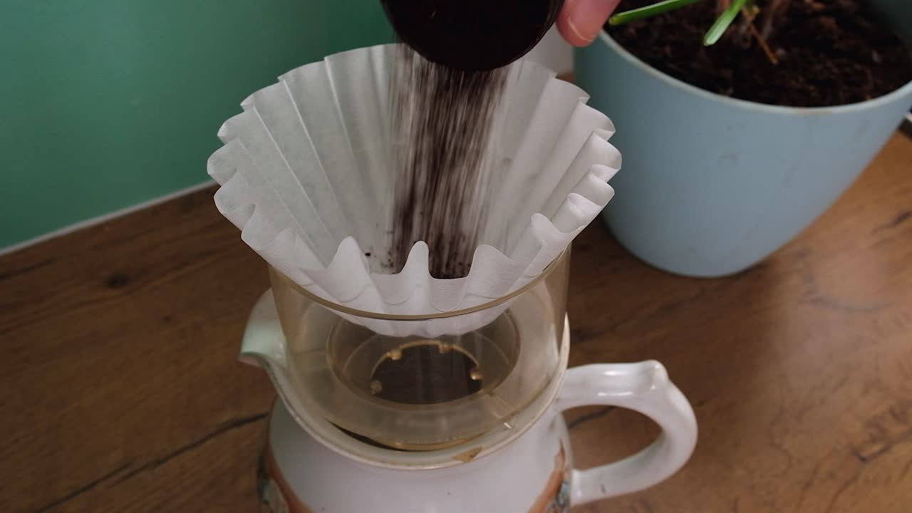 Close up: Ground coffee poured into basket filter on small coffee pot