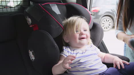 Madre-Poniendo-A-Su-Hija-En-Un-Asiento-De-Seguridad-En-Un-Viaje-En-Coche