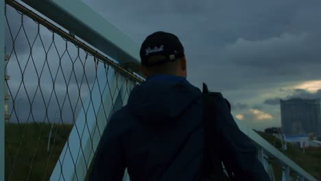 man with cap walks towards scheveningen beach during sunset, in 1000fps super slowmotion