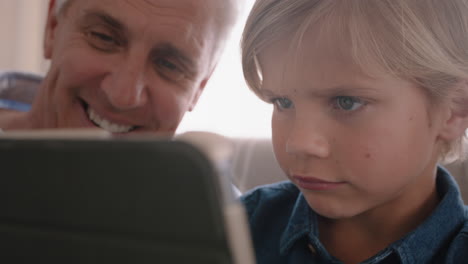 Großvater-Zeigt-Einem-Kleinen-Jungen,-Wie-Man-Einen-Tablet-Computer-Benutzt,-Und-Bringt-Seinem-Neugierigen-Enkel-Moderne-Technologie-Bei.-Intelligentes-Kind-Lernt-Ein-Mobiles-Gerät,-Das-Mit-Opa-Auf-Dem-Sofa-Sitzt.-4k