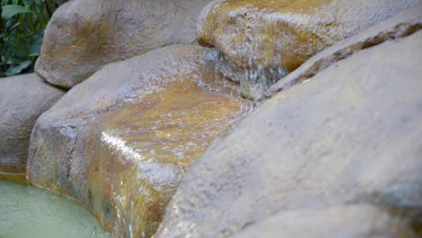 Running-water-into-over-rock-into-outdoor-pool-rock-fountain