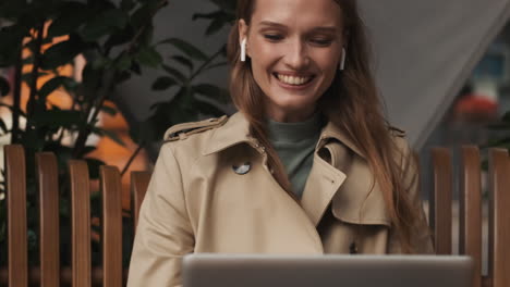 una mujer caucásica llamando por video en una computadora portátil al aire libre.