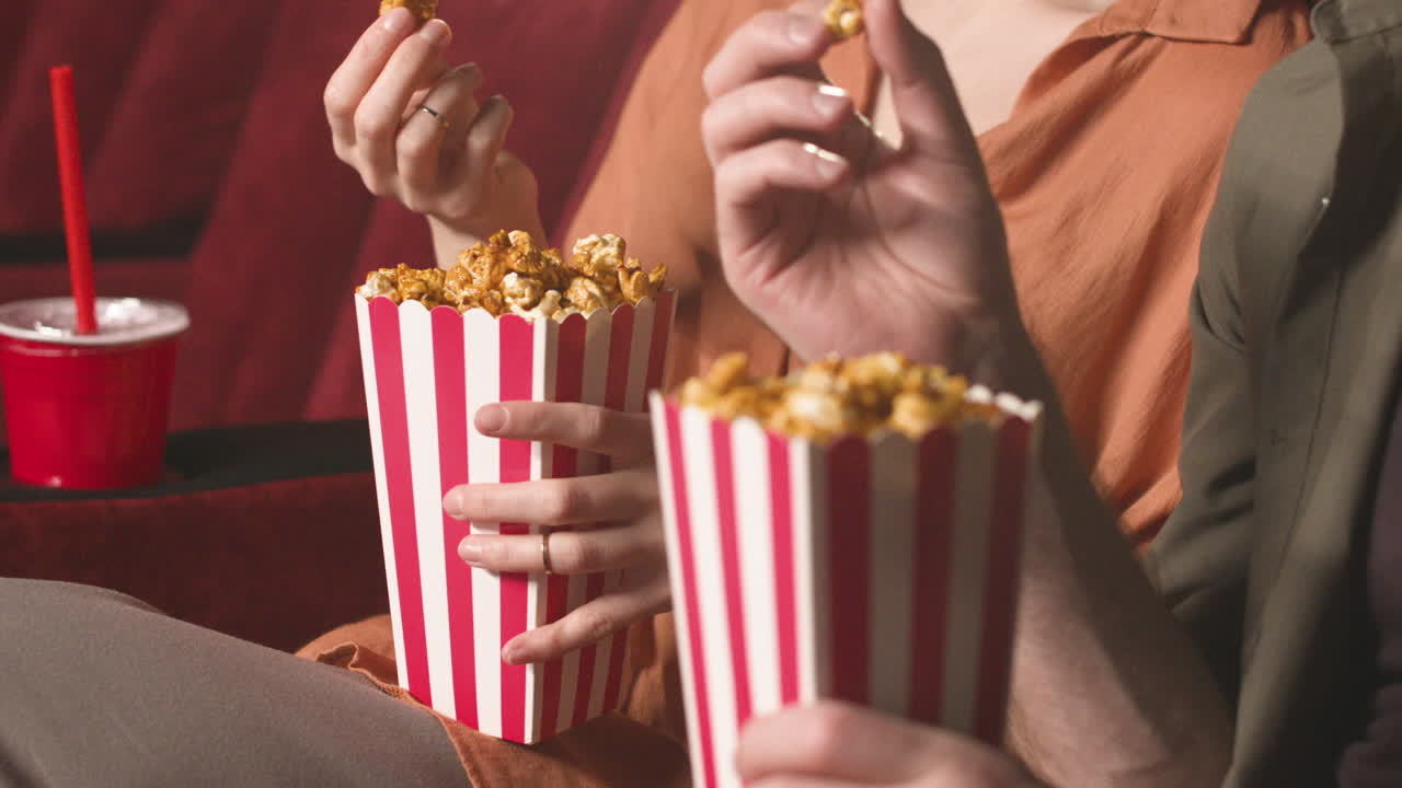 Close Up View Of Couple Hands Holding Popcorn In The Cinema