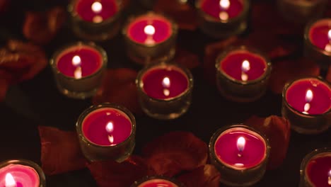 romantic lit red candles revolving on background covered in rose petals