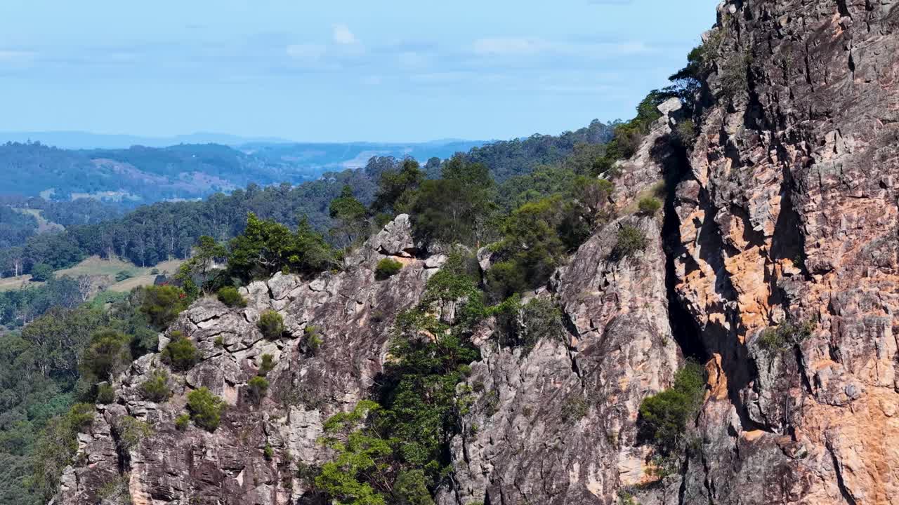 Drone footage captures Nimbin Rocks' rugged formations and lush eucalyptus forest under clear skies, showcasing Australia's natural beauty