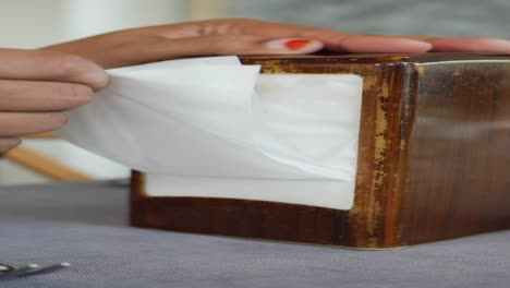 person cleaning a wooden tissue box with a tissue