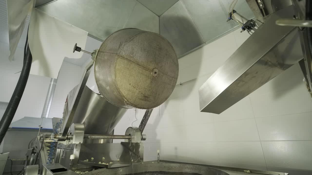 máquina de fritura industrial, las papas fritas se fríen en un cuenco grande con aceite. producción de papas fritas y bocadillos.