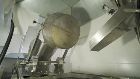 industrial deep frying machine, chips are fried in a large bowl with oil. production of potato chips and snacks.