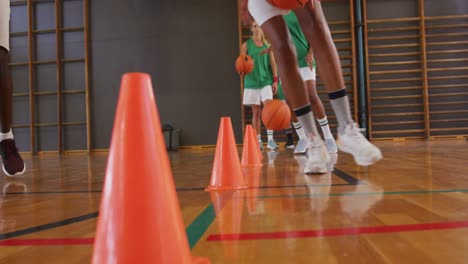 mid section of diverse female basketball team and coach practice dribbling ball