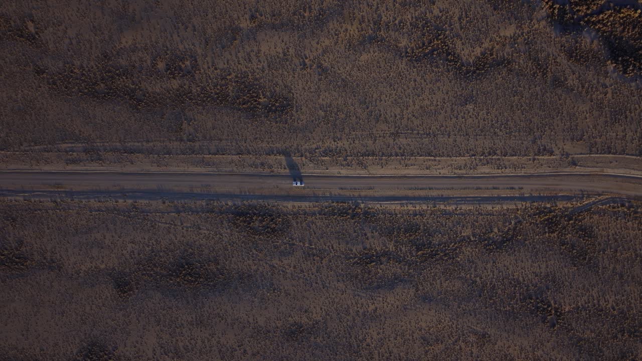 Veduta aerea ravvicinata dell'Autostrada 93 che attraversa un'arida conca dell'Idaho sotto una catena montuosa.