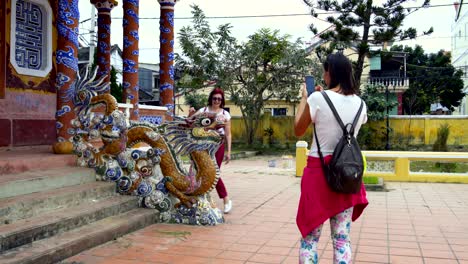 women are photographed with a dragon statue