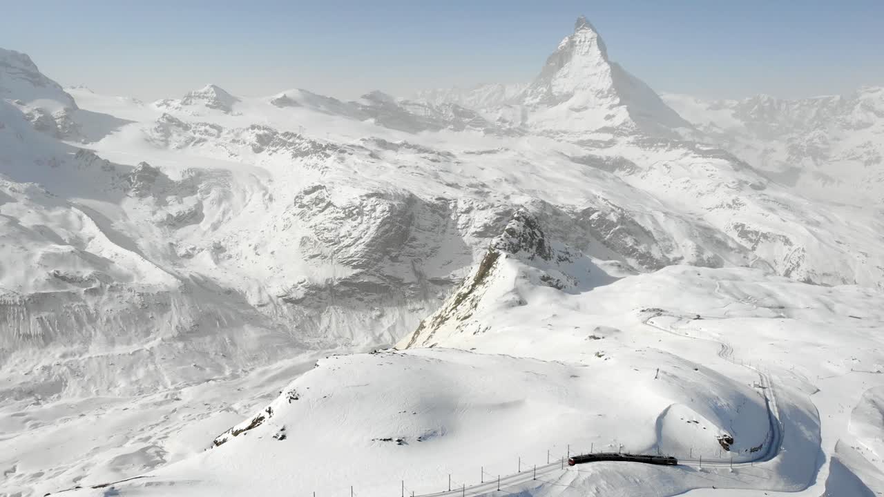 Aerial flyover over Gornergrat during winter with a view of the Matterhorn and a descending train