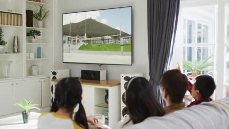 composite of happy family sitting at home together watching athletics high jump event on tv