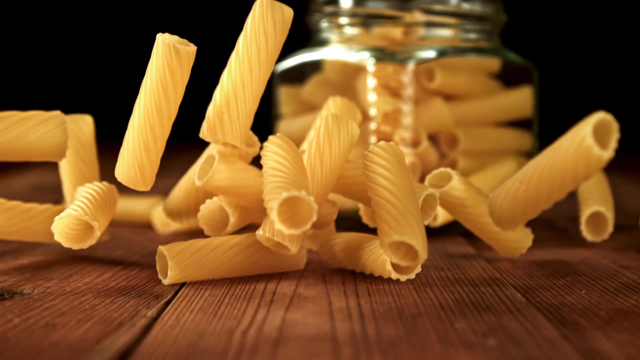 Pasta secca che cade su un tavolo di legno al rallentatore