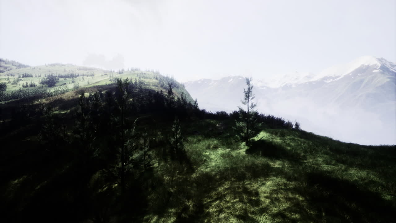 Vast green hills under a cloudy sky with distant snow capped mountains