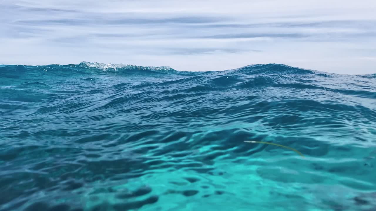 pov mira las olas de la superficie medio bajo el agua del mar caribe con burbujas y reflejos del cielo, los rocas