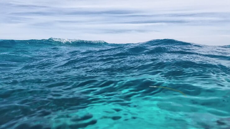 Vista POV delle onde in superficie, metà sott'acqua nel Mar dei Caraibi, con bolle e riflessi del cielo, Los Roques