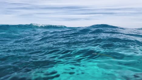 POV-watch-waves-Surface-half-underwater-caribbean-Sea-With-bubbles-and-Sky-Reflections,-Los-Roques