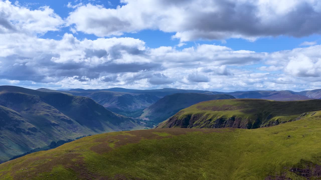 Drone camera smoothly pans across lush mountain ridge under partly cloudy daylight in Scottish Highlands