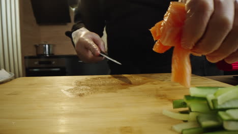 chef preparing fresh salmon and vegetables for sushi