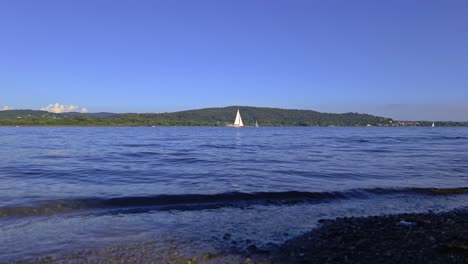 cinematic low-angle view of yacht cruise in calm open lake waters of maggiore lake in italy