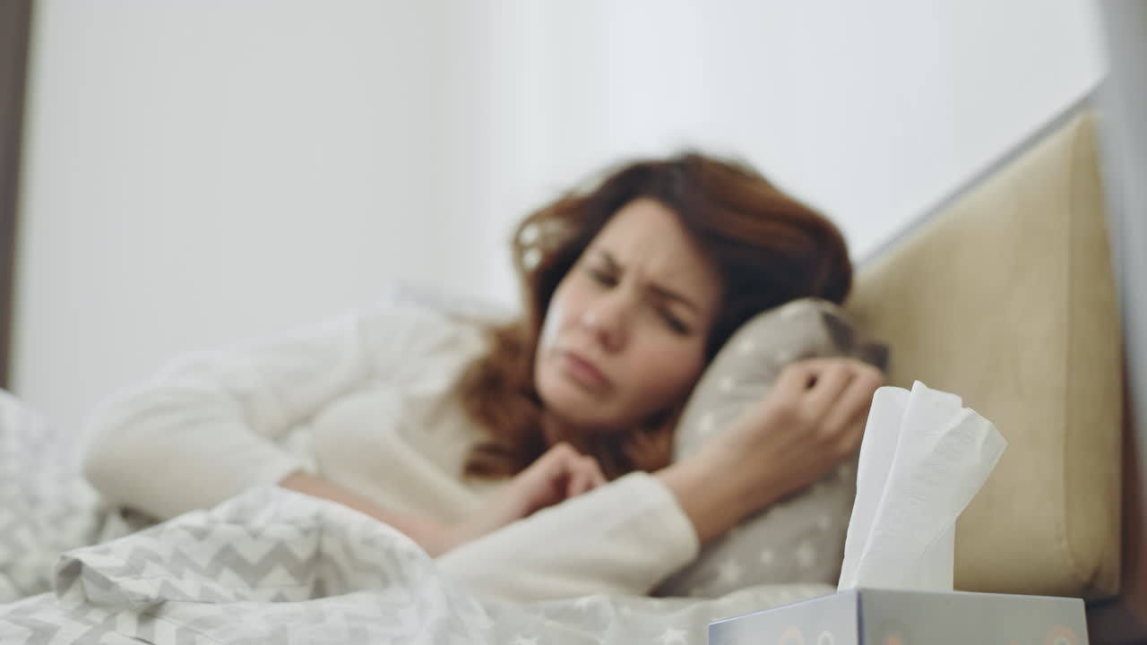 Donna malata che si sente male in camera da letto. Una donna malata starnutisce a letto.