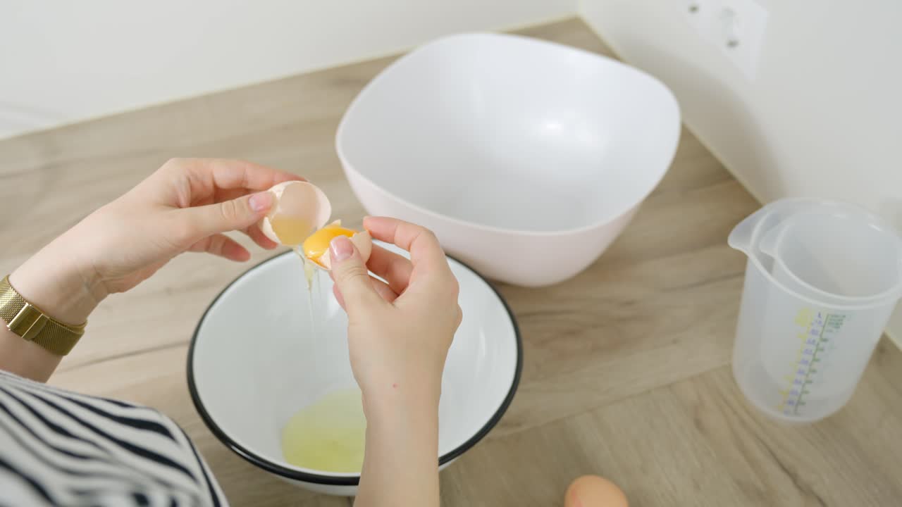 Opening an egg and separating the whites from yolks as part of the tiramisu dessert prep