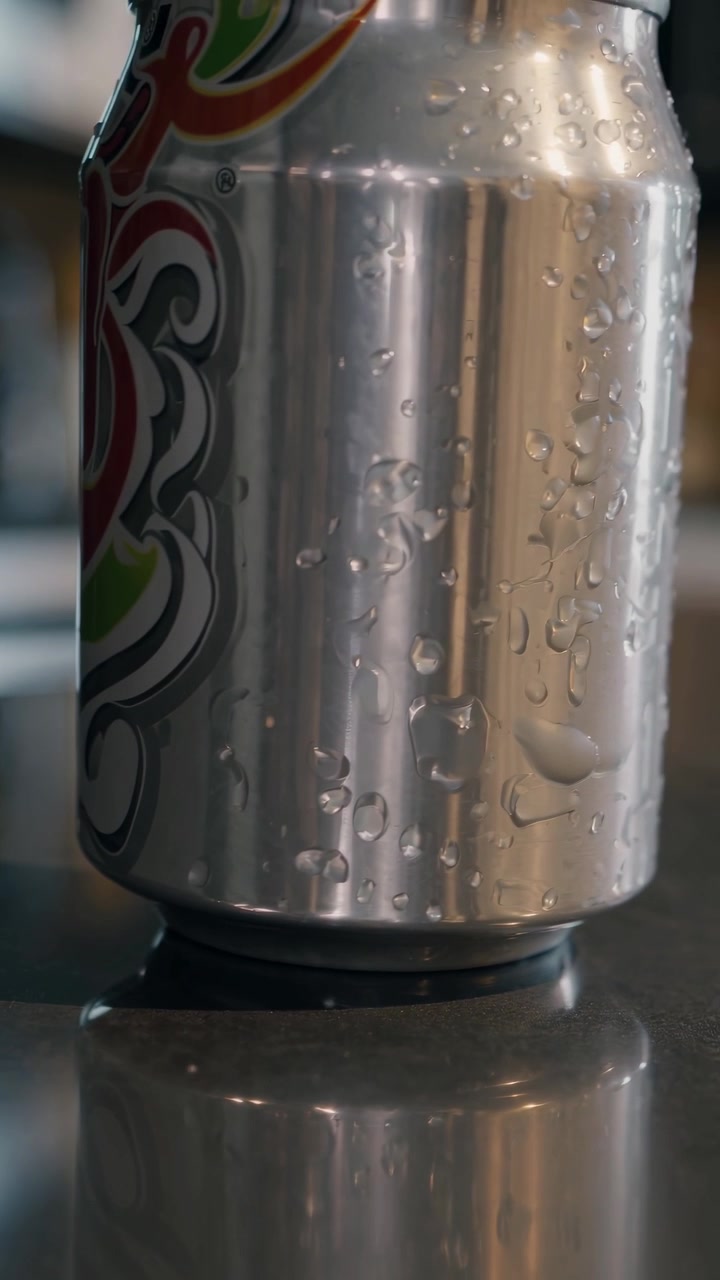Lata de refresco de aluminio fría con condensación sobre una superficie oscura