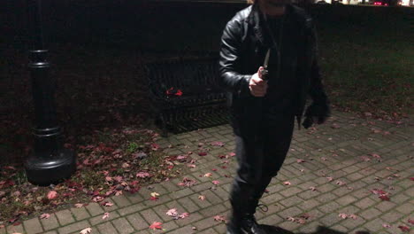 a person in a park at night pulling out a knife