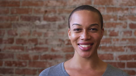 portrait of smiling african american woman standing against brick wall in coffee shop