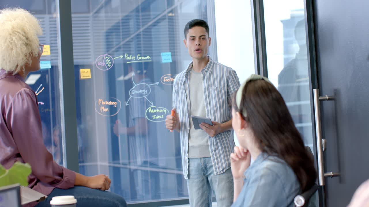 Presenting business strategy, man holding tablet, discussing with colleagues in office