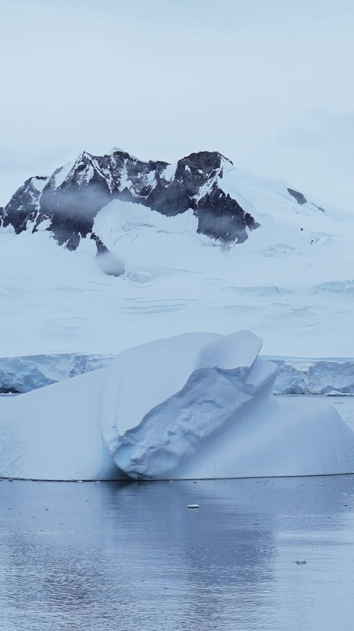 Icebergs azules y montañas de la Antártida. Iceberg flotando en el agua del océano en video vertical para redes sociales, Instagram Reels y Tiktok. Paisaje invernal marino de hielo de la Península Antártica.