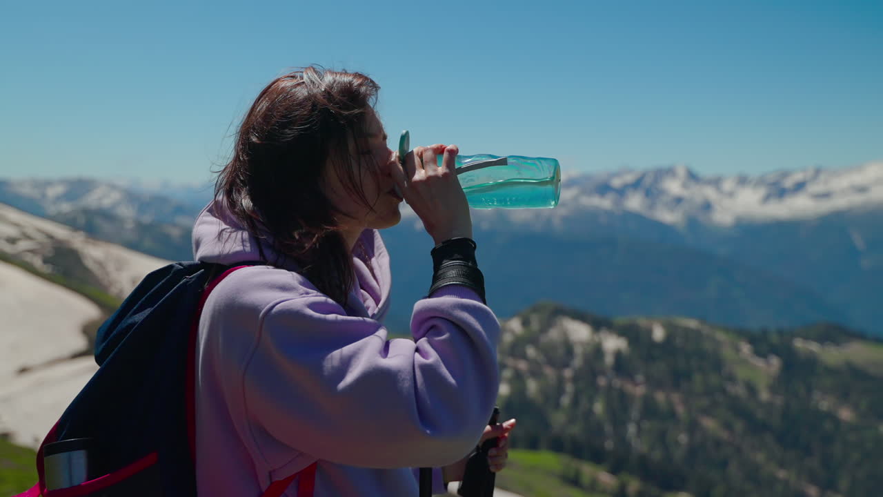 mujer caminando por las montañas, bebiendo agua