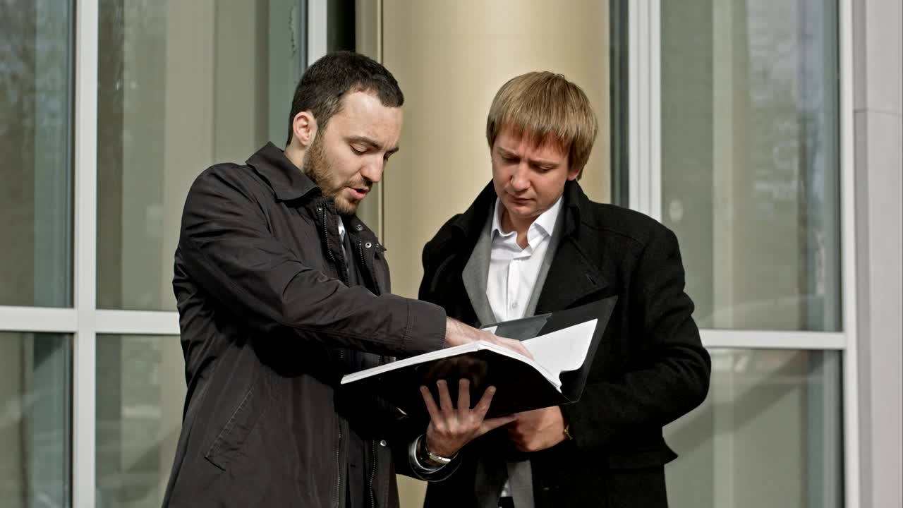 два бизнесмена смотрят на бумаги.