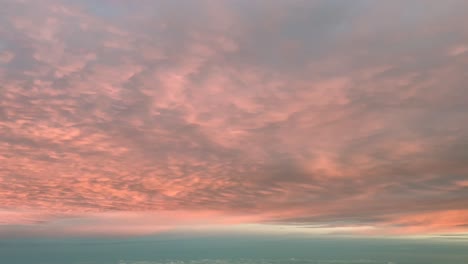 POV-Flug-Unter-Intensiv-Orangefarbenen-Wolken,-Aufgenommen-Aus-Einer-Flugzeugkabine-Bei-Sonnenaufgang