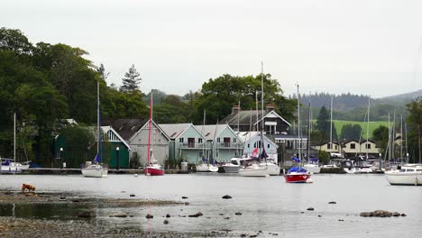 a boathouse with moored yachts on the tranquil shores of lake windermere in the lake district national park in cumbria, england, uk