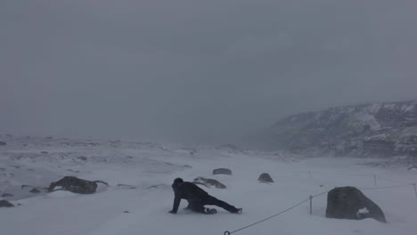 rückansicht, mann rutscht aus und fällt auf eis in kalter, verschneiter, windiger winterlandschaft