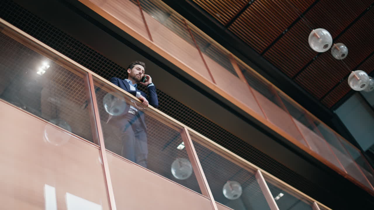 Elegant ceo talking mobile phone standing at glass balcony company office