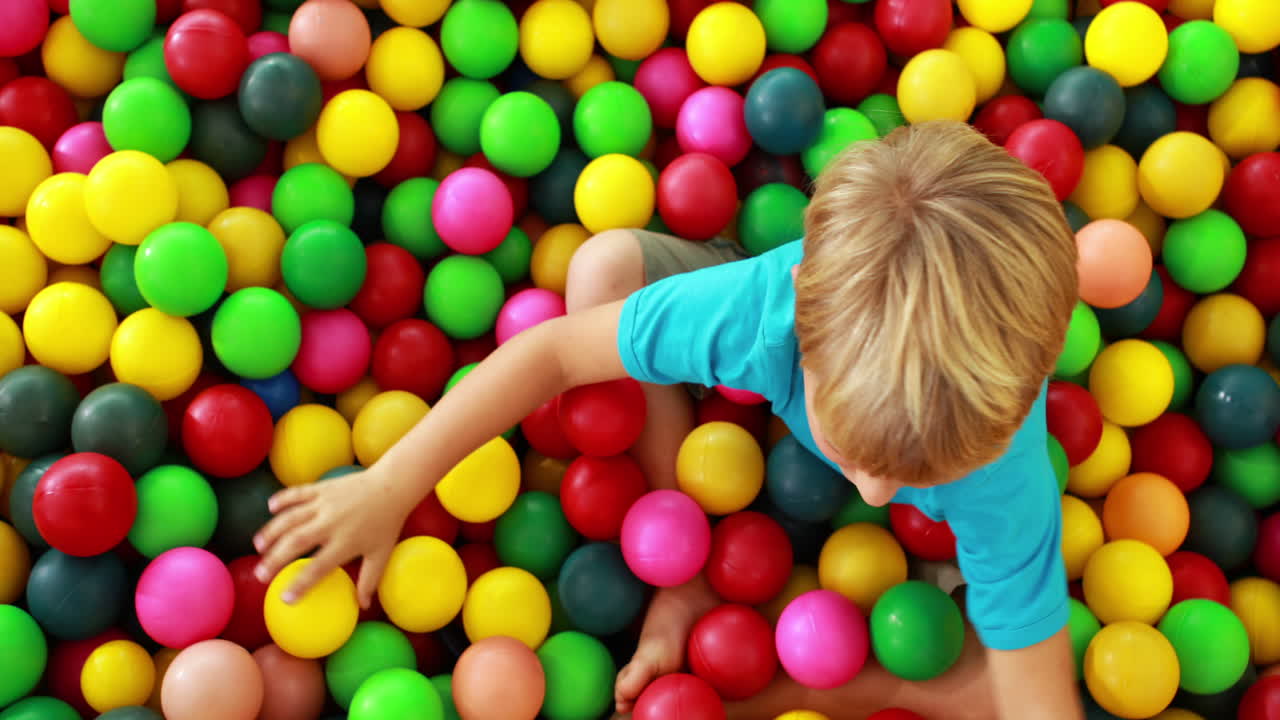 un niño lindo jugando y divirtiéndose en la piscina de pelota