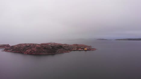 lysekil, sweden - small island with colorful houses on the coast surrounded by calm sea water under the cloudy sky - wide shot