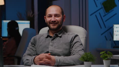 Portrait-of-smiling-businessman-sitting-at-desk-table-in-business-company-office