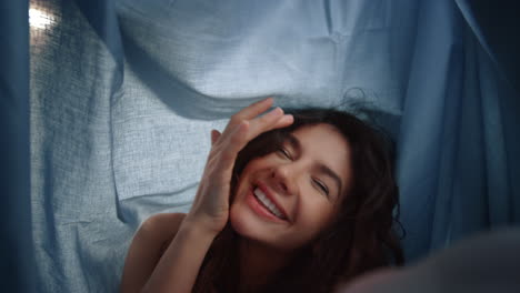 woman laughing below sheet