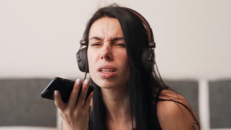 portrait-of-a-beautiful-charismatic-girl-in-headphones-talking-on-a-smartphone