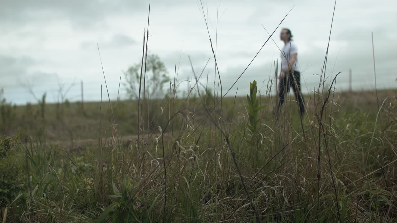 Man walking on dirt road by expansive fields