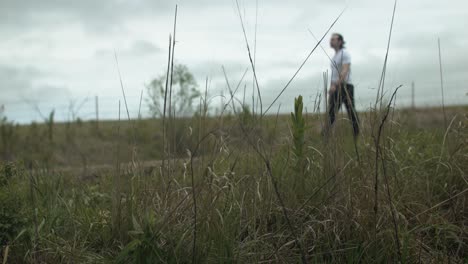 man walking on dirt road by expansive fields