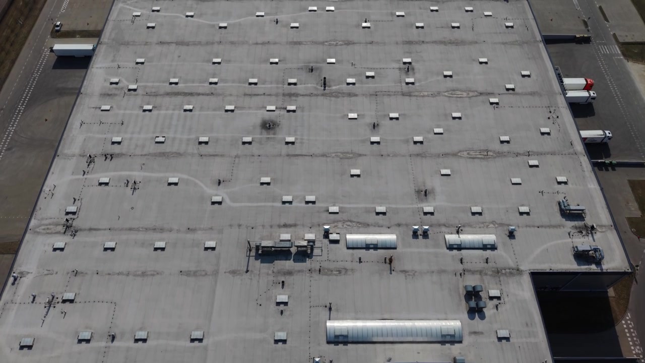 Drone Aerial Warehouse Rooftop Showing Hvac Vents, Maintenance Technicians Conducting Inspection, Gray Concrete Expanse, Rooftop Units, Access Hatch, Service Vehicles In Yard, Supply Chain