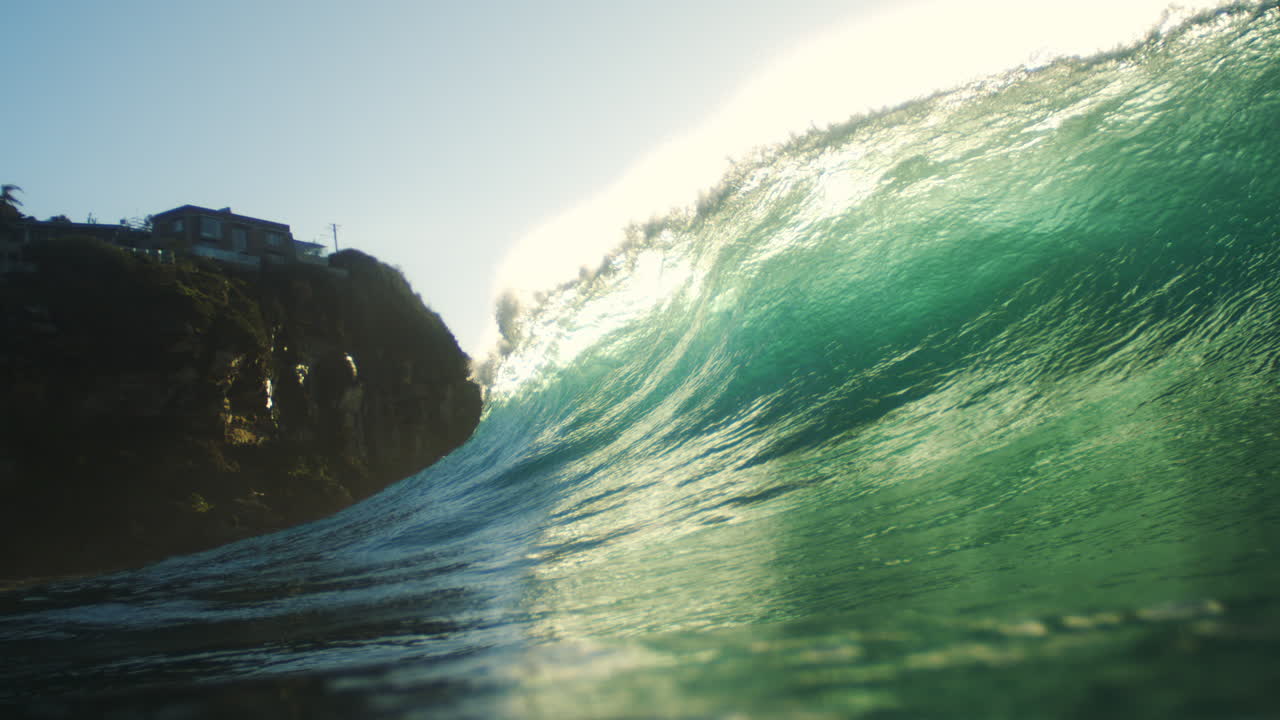 Slow motion backlit wave glows bright green with smooth crest